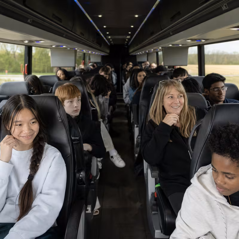 Group boarding a white charter bus for School Transportation transportation in Norfolk